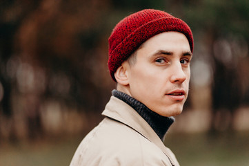 A close-up portrait of a tourist guy. A traveler in a red knitted hat turns back.