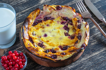 Sweet cottage cheese casserole with gooseberry and semolina on wooden table. Ceramic bowl with baked cottage cheese casserole