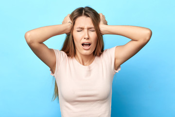 Frustrated angry unhappy sad nervous woman screaming touching her head. close up photo. facial expression, reaction , girl has terrible headache. health problem. isolated blue background