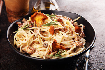 pasta with organic chanterelles. portion of spaghetti pasta with fried chanterelles in a creamy garlic sauce with cheese on a table