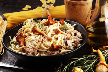 pasta with organic chanterelles. portion of spaghetti pasta with fried chanterelles in a creamy garlic sauce with cheese on a table