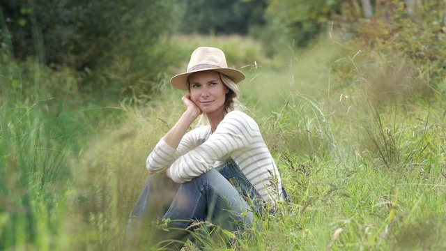 Smiling farmer woman relaxing in field