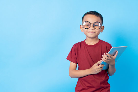 Asia Thai Boy Student Holding Tablet Looking Camera Isolated On Blue Background In Studio