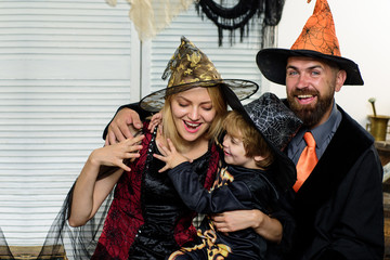 Happy family preparing for Halloween. Children wearing black and orange witch costumes with hats playing with pumpkin and spider in Halloween. Kids trick or treat.