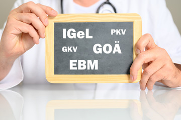 Arzt mit einer Tafel auf der GOÄ, Igel, EBM usw. steht