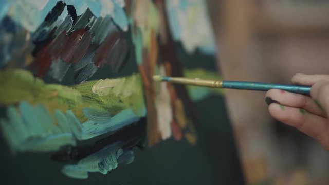 Detail view of brush of artist, touching canvas, drawing a picture