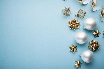 Fototapeta na wymiar Christmas and New Year holiday background. Xmas greeting card. Christmas white golden ornaments on blue background top view. Flat lay