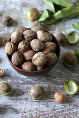 Inshell walnuts in a bowl. Harvest walnuts. The leaves of the walnut tree. Walnuts in a green peel. Selective focus. Macro.