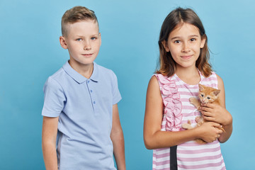 Fototapeta premium little girl and boy spending time with a pet in the room with blue wall, animal concept.