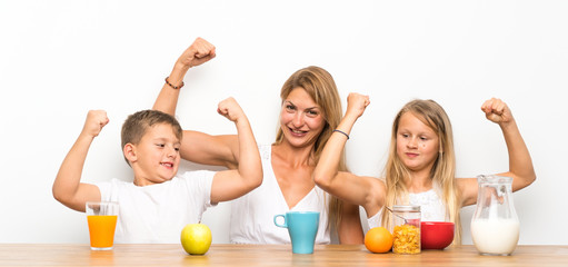 Mother with her two children having breakfast and making victory gesture