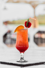 Alcoholic cocktail with orange and strawberry in a glass closeup