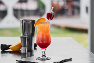 Alcoholic cocktail with orange and strawberry in a glass, a party on the beach