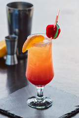 Two-layered alcoholic cocktail in a glass with orange and strawberry, a party on the beach