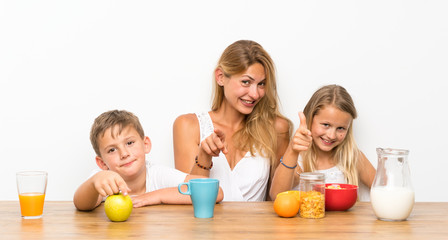 Mother with her two children having breakfast and  pointing to the front