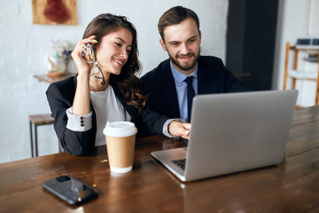 cheerful woman and handsome man in elegant suits watching funny video, readng interesting information, during coffee break. close up photo