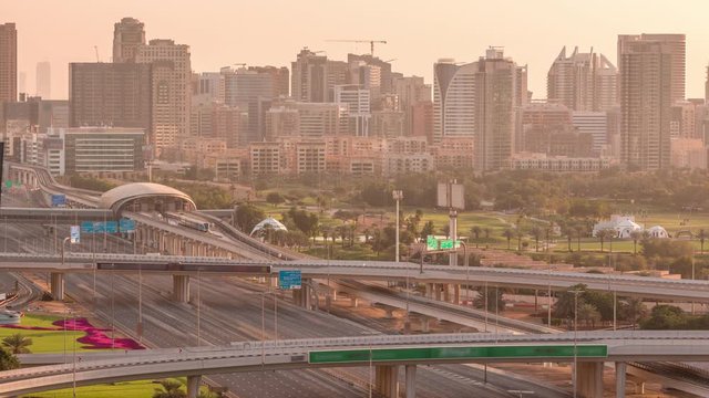Dubai Golf Course with a cityscape of Gereens and tecom districts at the background aerial timelapse early morning during sunrise. Traffic on sheikh zayed road with junction