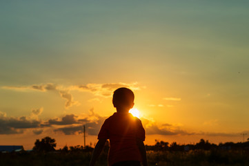 Fototapeta premium Silhouette of a boy against the backdrop of the setting sun