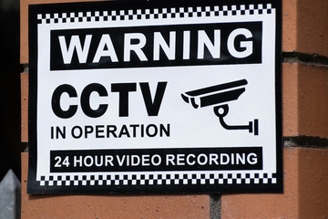 View of Warning CCTV in operation 24 hour video recording sign on brick wall