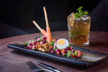 Christmas cockatail with ice and mint and salad with egg and berry on wood table