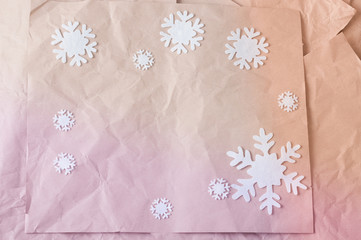 Pile of colorful rumpled kraft paper lying in disorder with white woolen snowflakes.