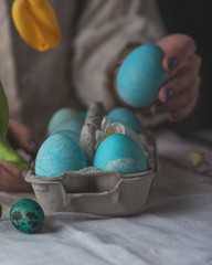 Woman hand giving easter egg in box to other easter eggs closeup