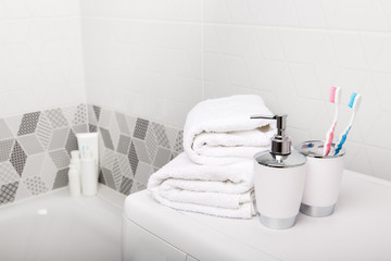 Obraz na płótnie Canvas Bathroom, body care products and towel. Bath preparation. White interior of bathroom. Shampoo, shower gel and other bathing accessories. Toothbrush and soap dispenser. details of bathroom interior