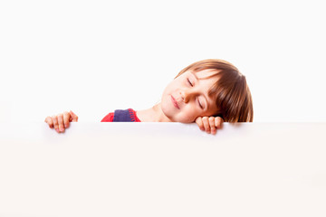 Cute sleepy little child girl behind white empty banner. Free space for text.