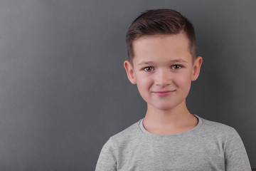 Cute brunette boy smile over grey background