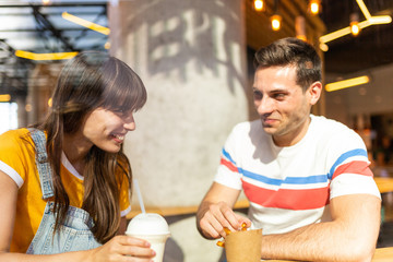 young couple smiling and eating food at restaurant