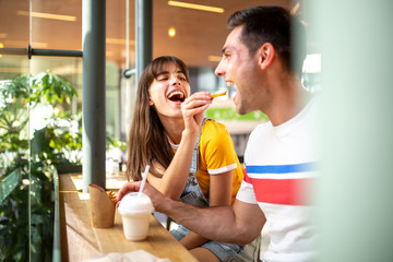 fun couple sitting at restaurant and eating food together