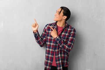 Man over grunge wall pointing with the index finger and looking up