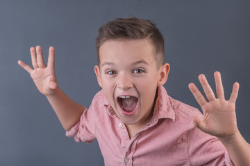 Funny brunette boy is building a frightening face, the concept of children's emotions closeup