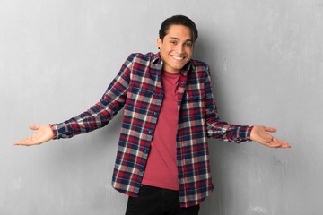 Man over grunge wall making unimportant gesture while lifting the shoulders