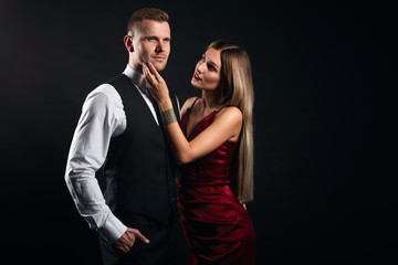 blonde woman touching her guy's cheek . supporting him , trying to calm him down. isolated black background