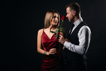 charming blonde woman in trendy red dress having a date with a rose. isolated black background, studio shot.family