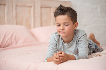 portrait of a funny brunette boy with a displeased face in the bedroom