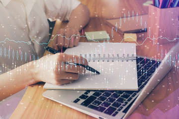 Fototapeta premium Financial charts displayed on woman's hand taking notes background. Concept of research. Double exposure