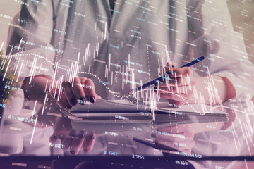 Financial forex graph drawn over hands taking notes background. Concept of research. Double exposure