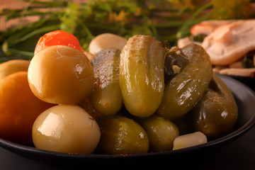 Pickled cucumbers and tomatoes on a background of fermented foods on a dark background. Low key. Close-up