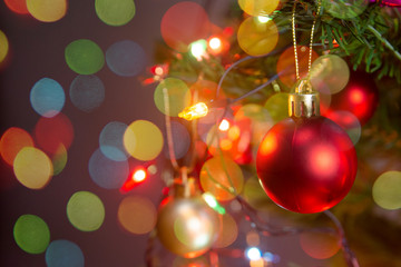 Fototapeta premium Christmas decoration. Hanging red balls on pine branches christmas tree garland and ornaments over abstract bokeh background with copy space.