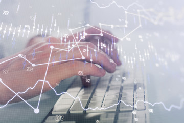 Double exposure of graph with man typing on computer in office on background. Concept of hard work. Closeup.