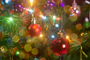 Christmas decoration. Hanging red balls on pine branches christmas tree garland and ornaments over abstract bokeh background with copy space.