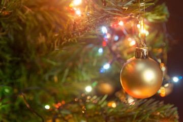 Christmas decoration. Hanging gold balls on pine branches christmas tree garland and ornaments over abstract bokeh background with copy space.