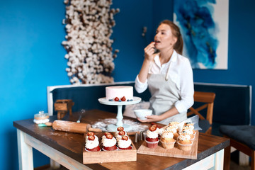 blonde woman eating berries while standing at the table, close up photo. treatment