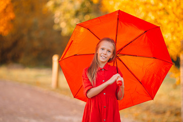 Obraz premium Happy child girl laughs under red umbrella