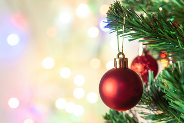 Christmas decoration. Hanging red balls on pine branches Christmas tree garland and ornaments over abstract bokeh background with copy space.