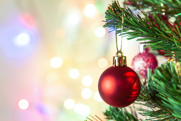 Christmas decoration. Hanging red balls on pine branches Christmas tree garland and ornaments over abstract bokeh background with copy space.