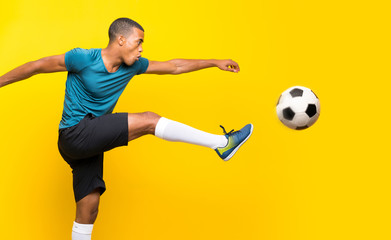 Naklejka na ściany i meble Afro American football player man over isolated yellow background