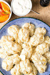 Manti on a large dish. Seasoning sour cream and pepper