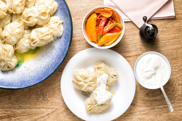 Manti on a large dish. Seasoning sour cream and pepper